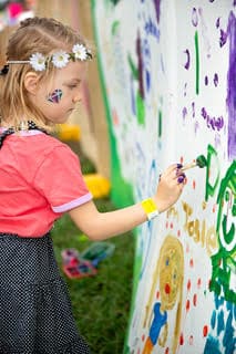 little girl is painting on a canvas